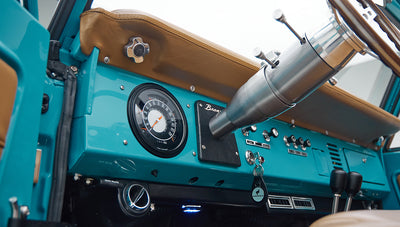 Close-up of steering column, ignition key, and AC vent beneath dashboard in Classic Ford Bronco
