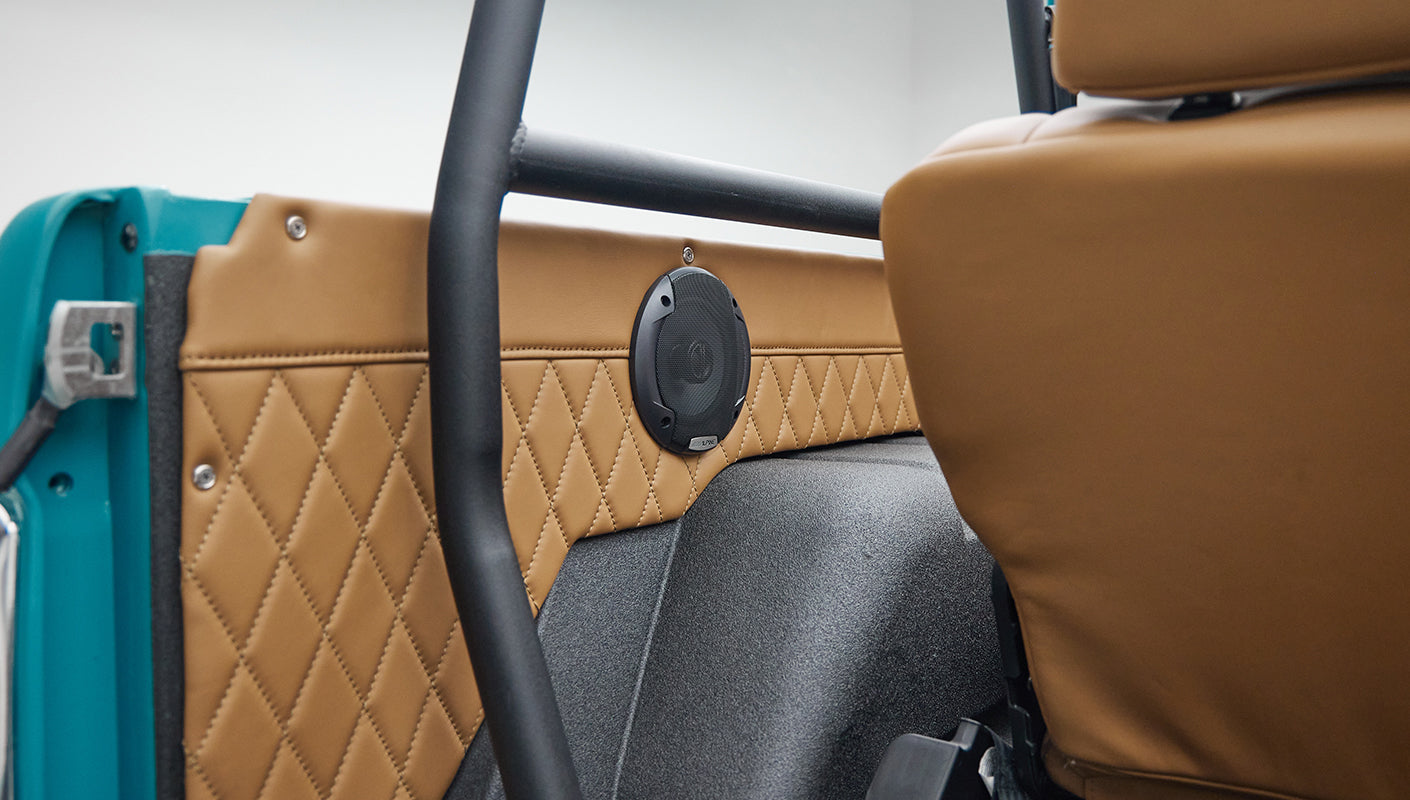 Bird's eye view of Classic Ford Bronco interior showing tan quilted seats and peacock blue door.