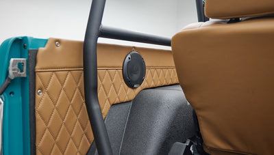 Bird's eye view of Classic Ford Bronco interior showing tan quilted seats and peacock blue door.