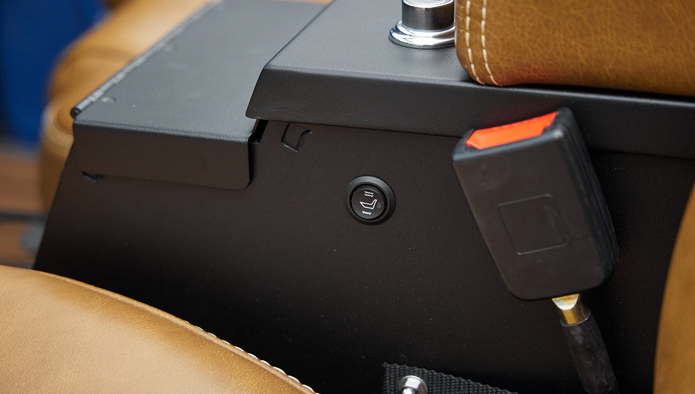 Close-up of a seat heater control button and tan leather upholstery inside Classic Ford Bronco