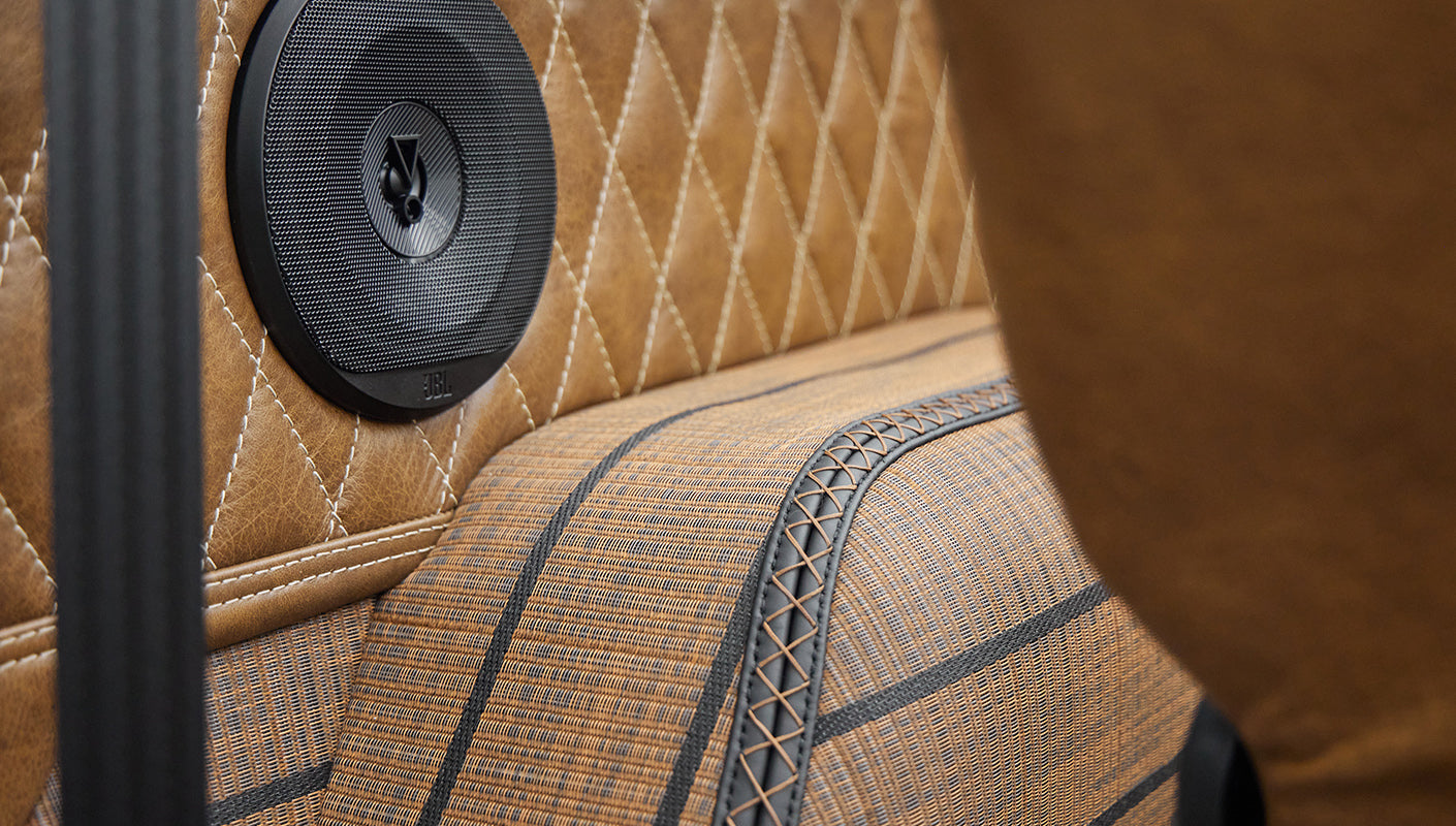 Close-up of tan diamond-stitched upholstery with a round speaker inside Classic Ford Bronco