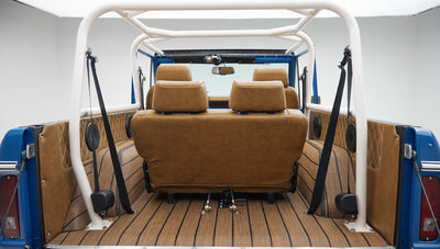 Rear view of tan leather seats with headrests and roll cage inside Classic Ford Bronco