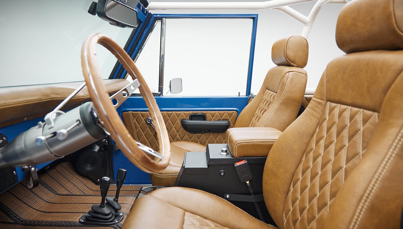 Interior close-up of Classic Ford Bronco with tan leather seats and blue door panel