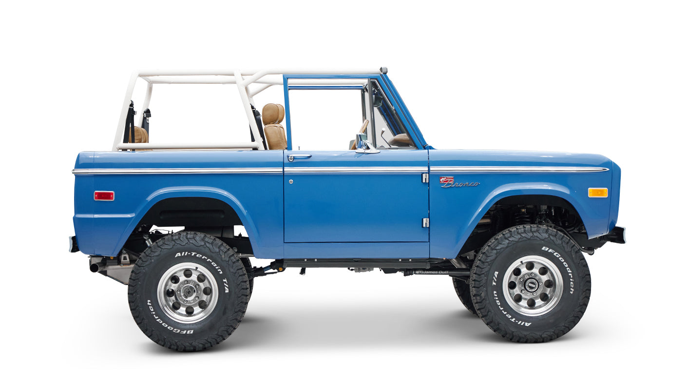 Side view of blue Classic Ford Bronco with door closed and white roll cage