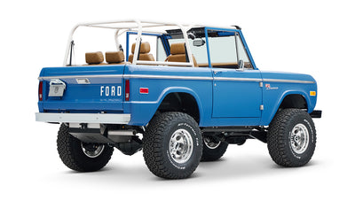 Rear side view of blue Classic Ford Bronco with white roll cage and brown seats