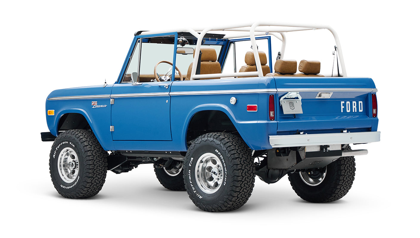 Rear three-quarter view of blue Classic Ford Bronco with white roll cage and lifted suspension