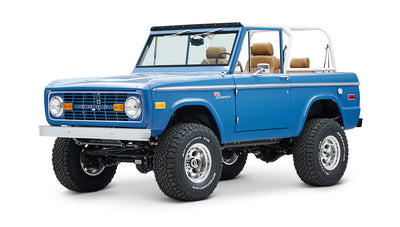 Side view of blue Classic Ford Bronco with white roll cage and tan interior