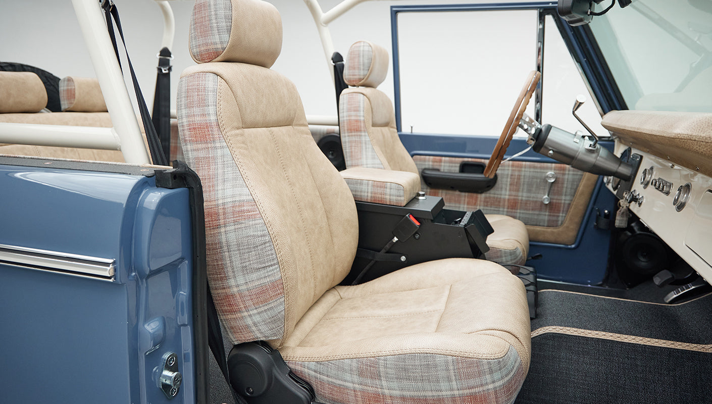 Classic Ford Bronco interior side view with two-tone plaid and beige seats and door panel
