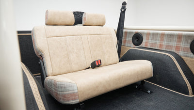 Rear bench seat in Classic Ford Bronco with beige fabric and visible seatbelt buckle
