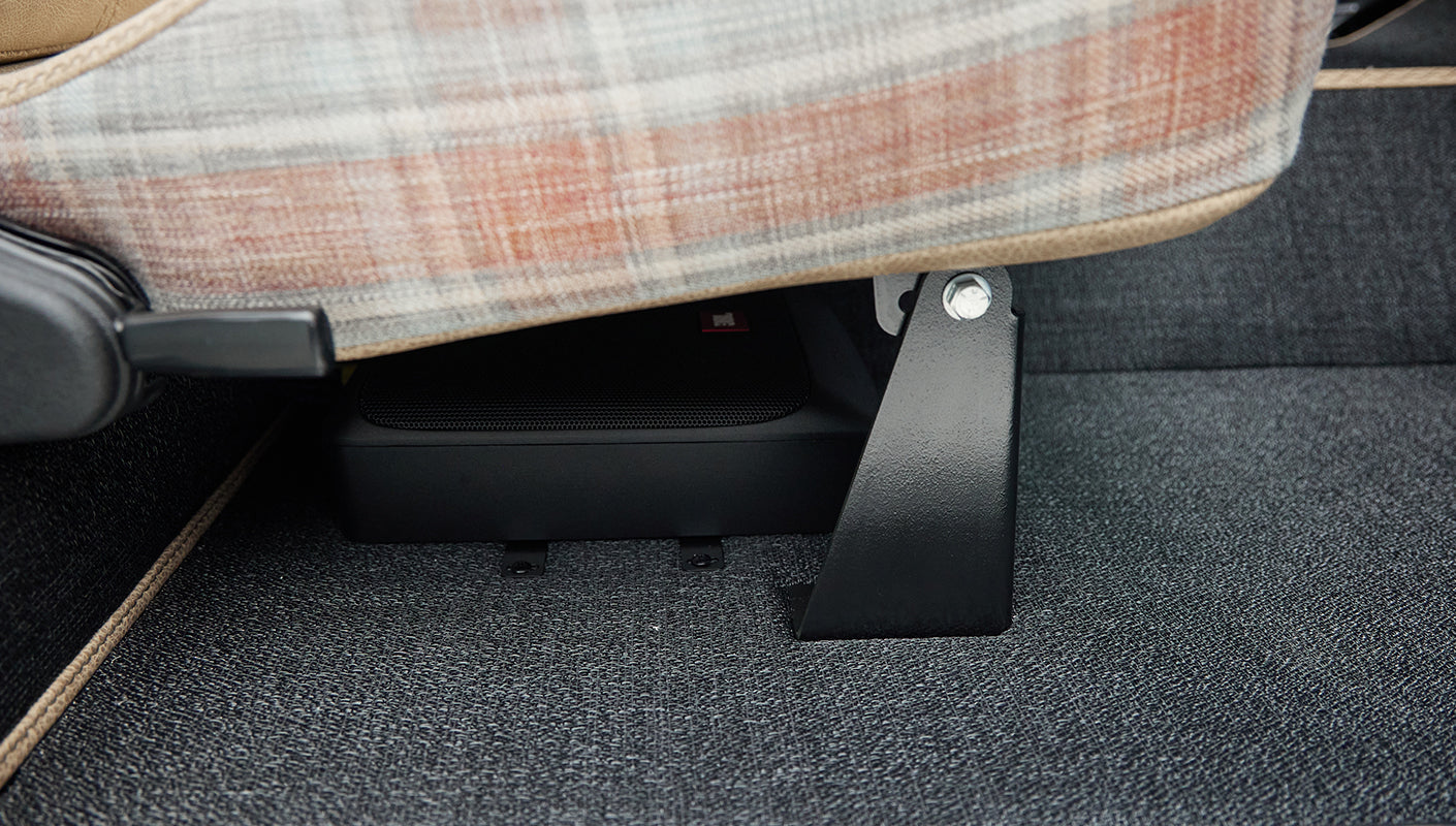 Under-seat area showing speaker and seat support bracket on carpeting