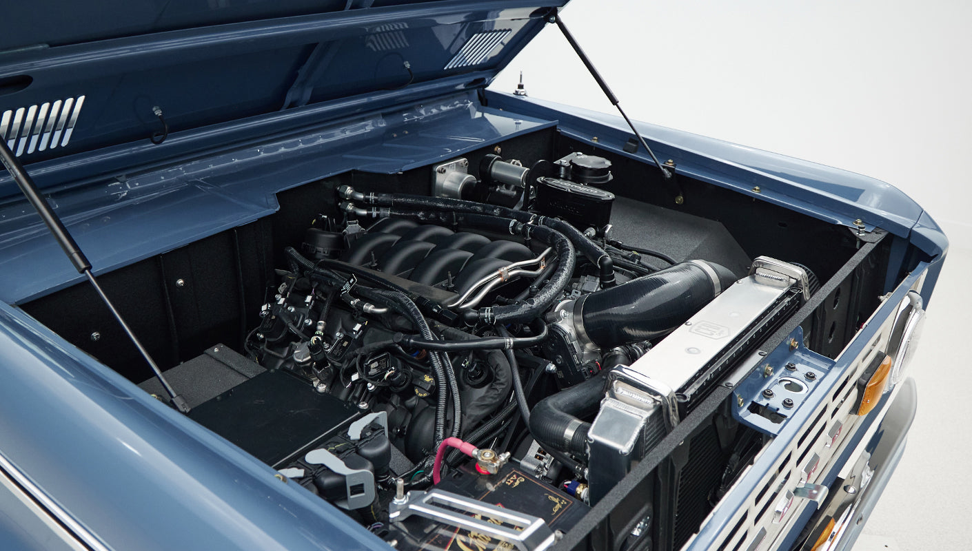 Engine compartment with blue hood raised showing black and silver engine components