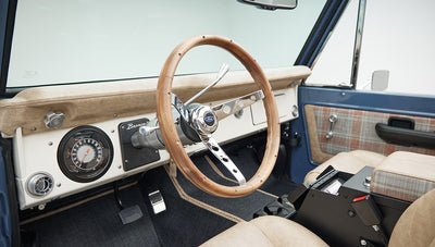 Classic Ford Bronco dashboard with wood-trimmed steering wheel and plaid seats