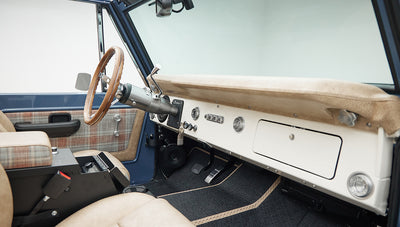 Full view of Classic Ford Bronco dashboard, wood steering wheel, beige plaid seats, and blue door