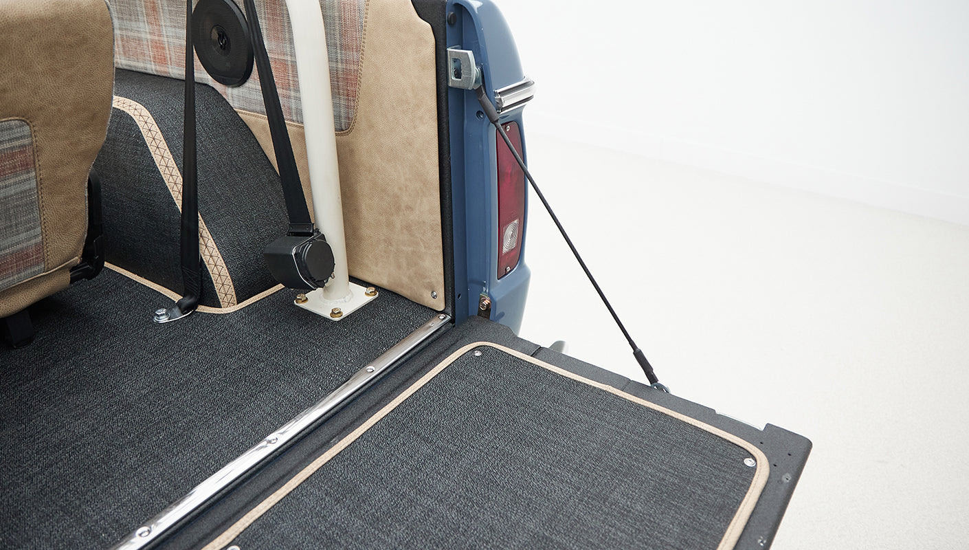 Interior rear section of Classic Ford Bronco with beige and plaid seats and black carpet