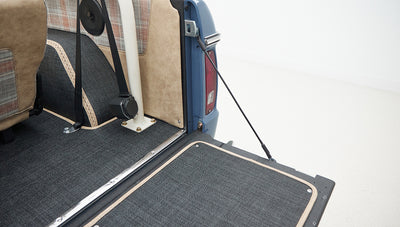 Interior rear section of Classic Ford Bronco with beige and plaid seats and black carpet