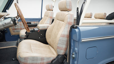 Classic Ford Bronco interior showing plaid and beige seats with center console and seatbelt
