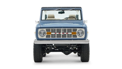 Classic Ford Bronco front view with blue body, rectangular headlights, and white convertible top