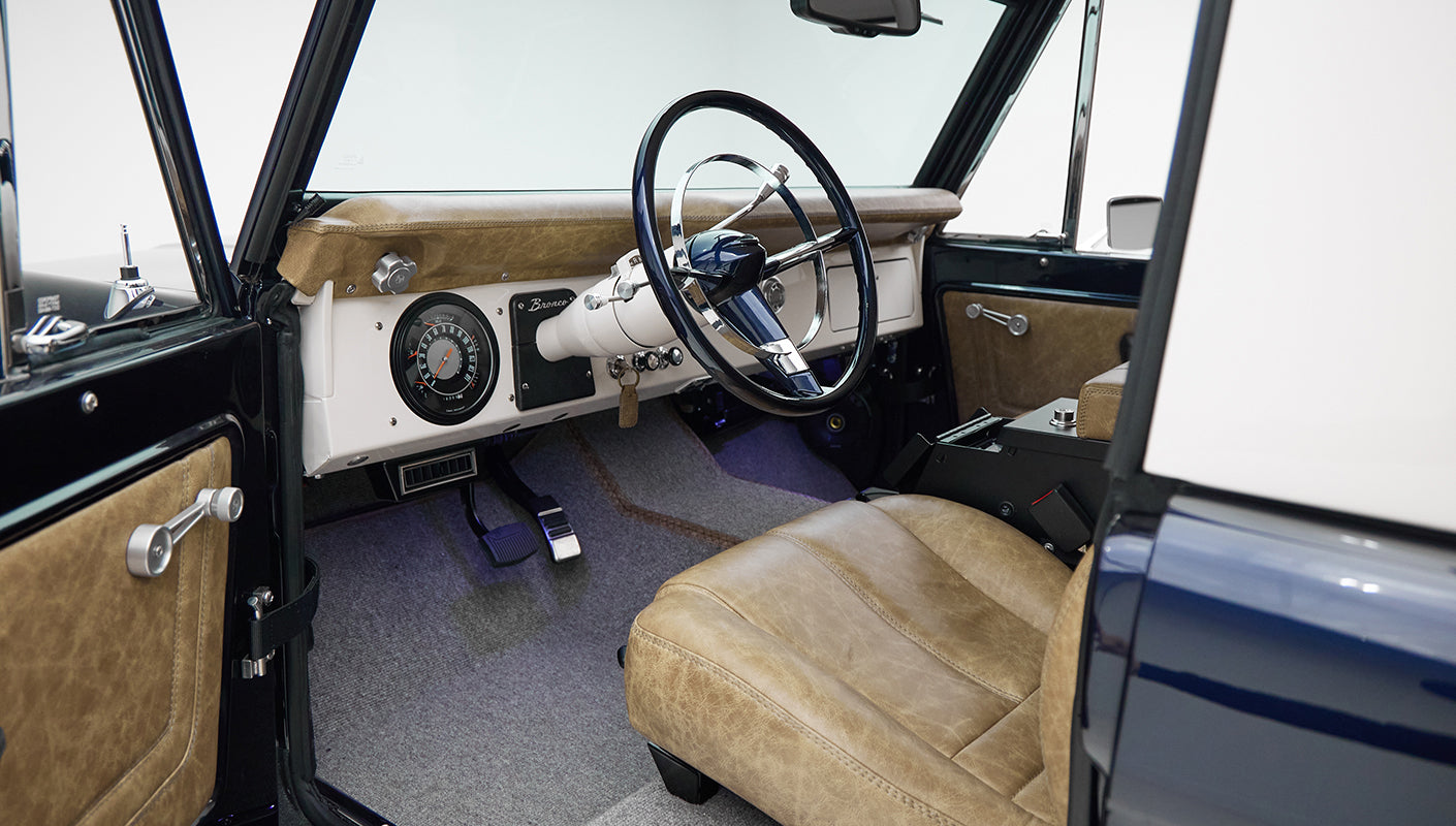 Driver seat of Classic Ford Bronco showing tan leather, steering wheel, and dashboard