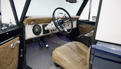 Driver seat of Classic Ford Bronco showing tan leather, steering wheel, and dashboard