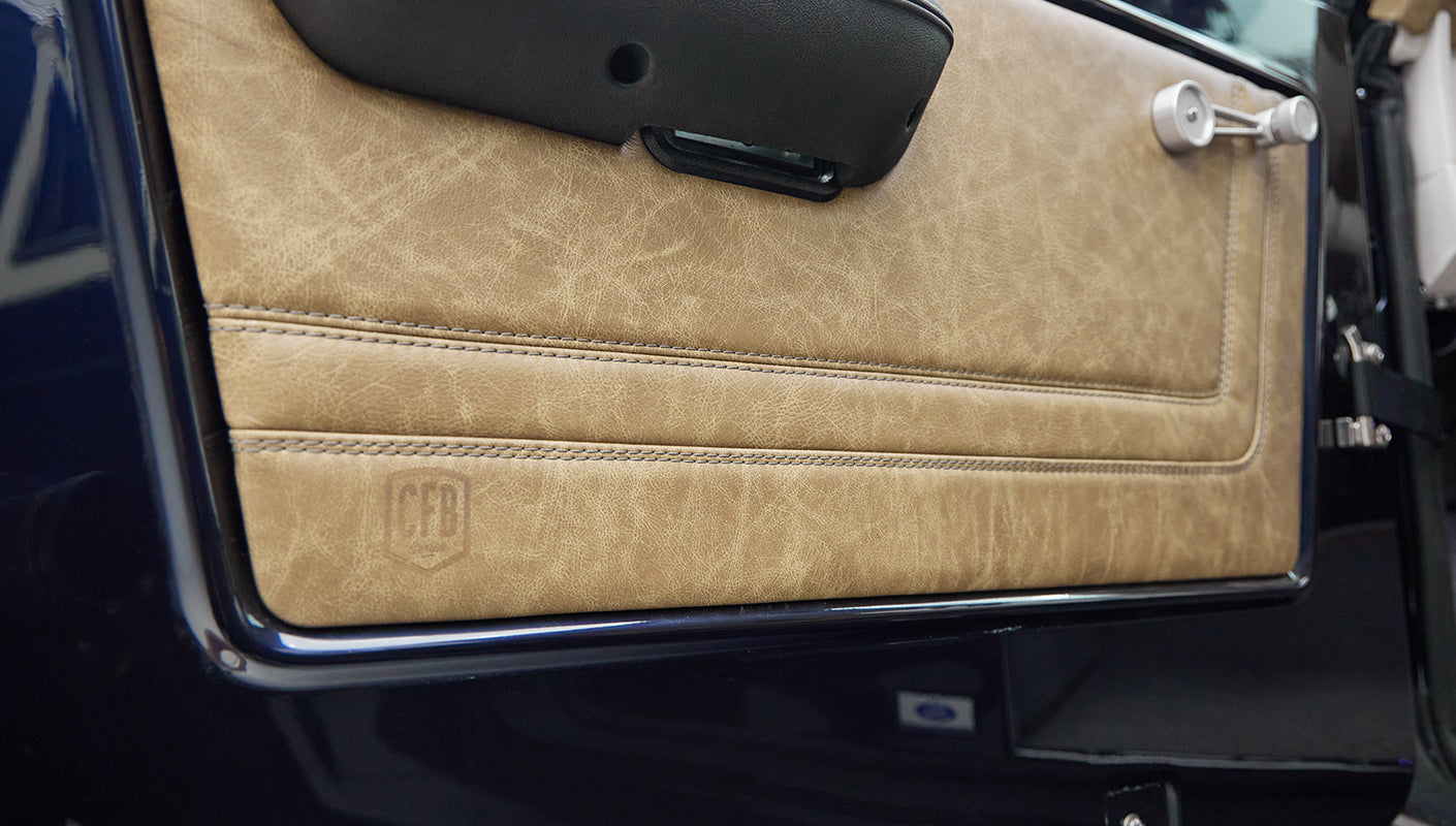 Close-up of tan leather door panel with visible stitching and CFB logo embossed