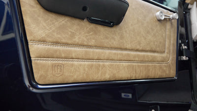 Close-up of tan leather door panel with visible stitching and CFB logo embossed