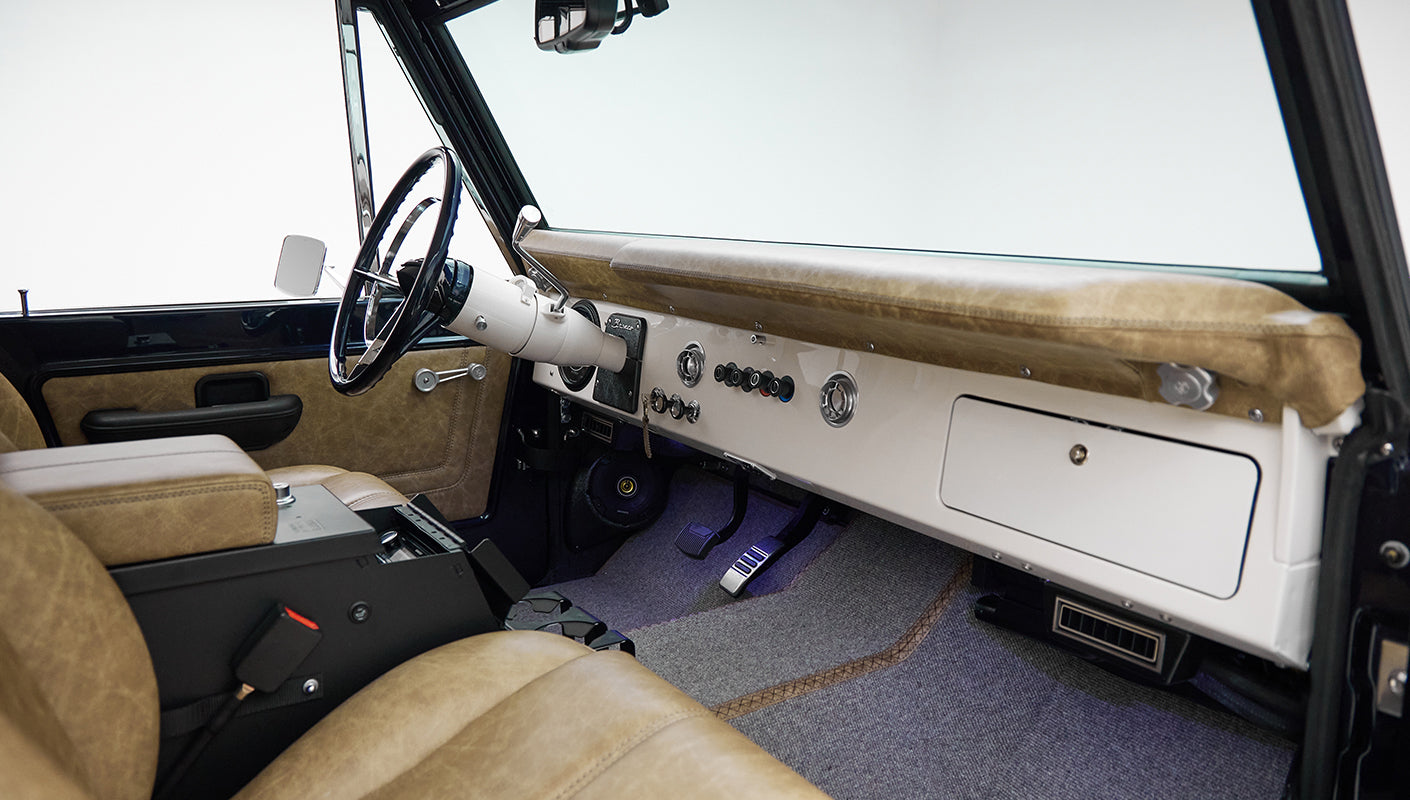 Interior dashboard and front seats of Classic Ford Bronco with tan leather upholstery and white dash