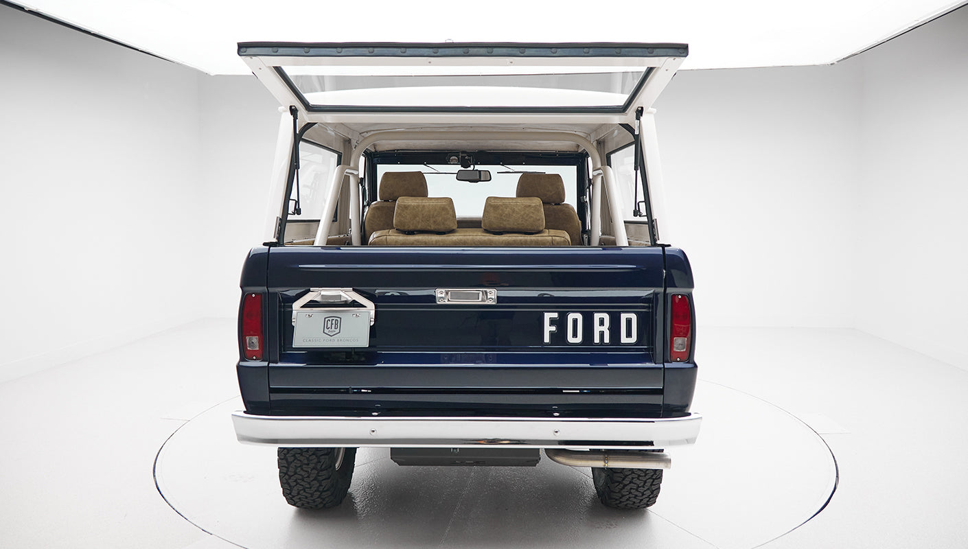 Rear view of Classic Ford Bronco with open back window and brown seats inside