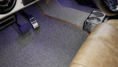 Floor pedals and gray carpeted floor with some purple lighting inside Classic Ford Bronco