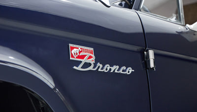 Side view of Classic Ford Bronco showcasing Sport Bronco emblem on dark blue door