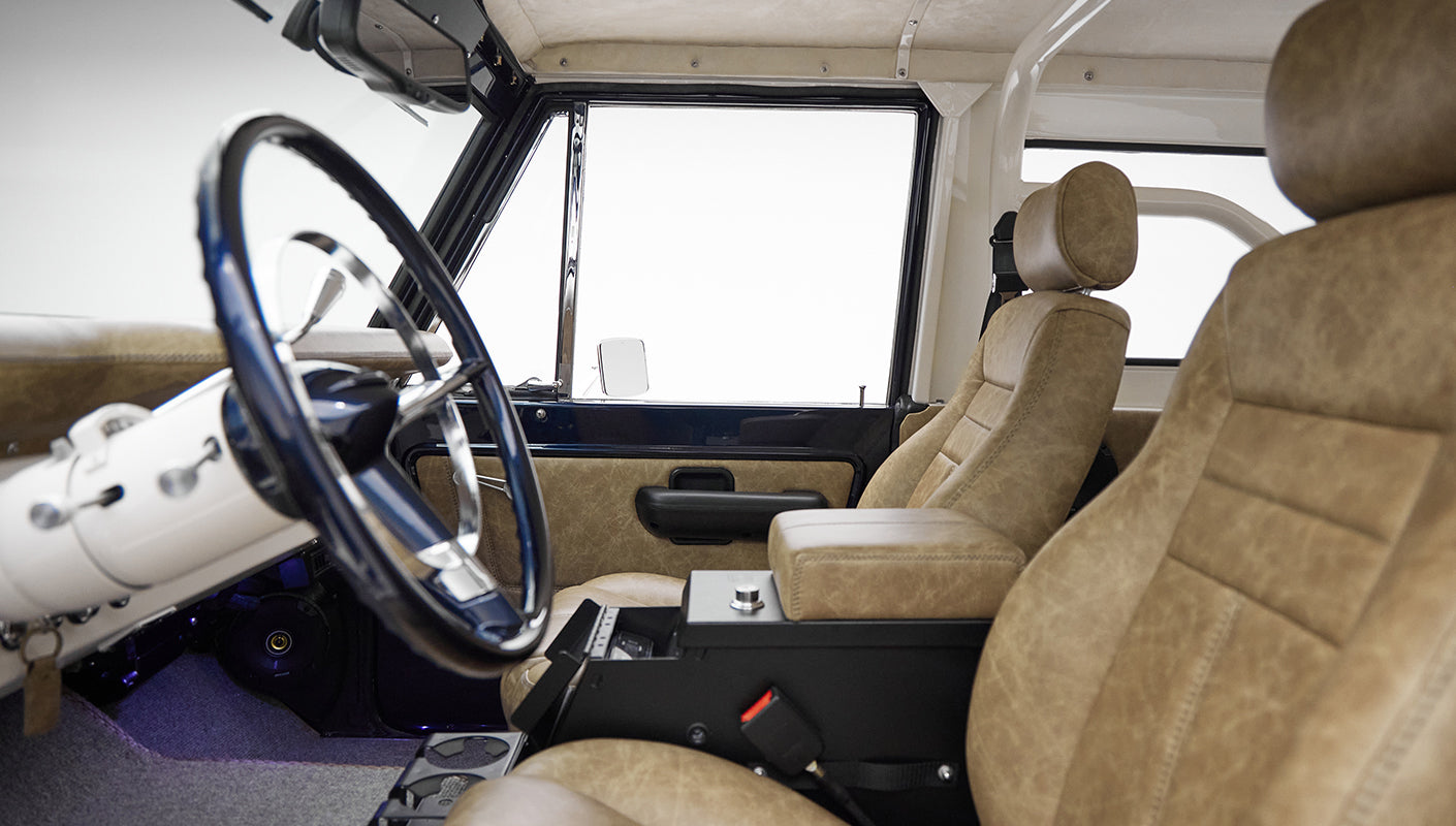 Interior front seats and steering wheel area of Classic Ford Bronco with tan leather and black accents