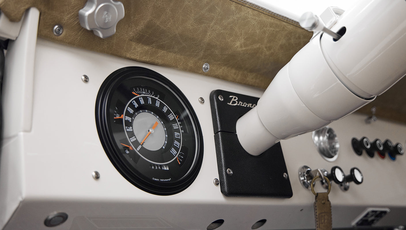 Instrument panel and ignition switch in Classic Ford Bronco with white and tan dashboard