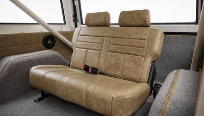 Rear seats of Classic Ford Bronco with tan leather upholstery and gray carpeted floor