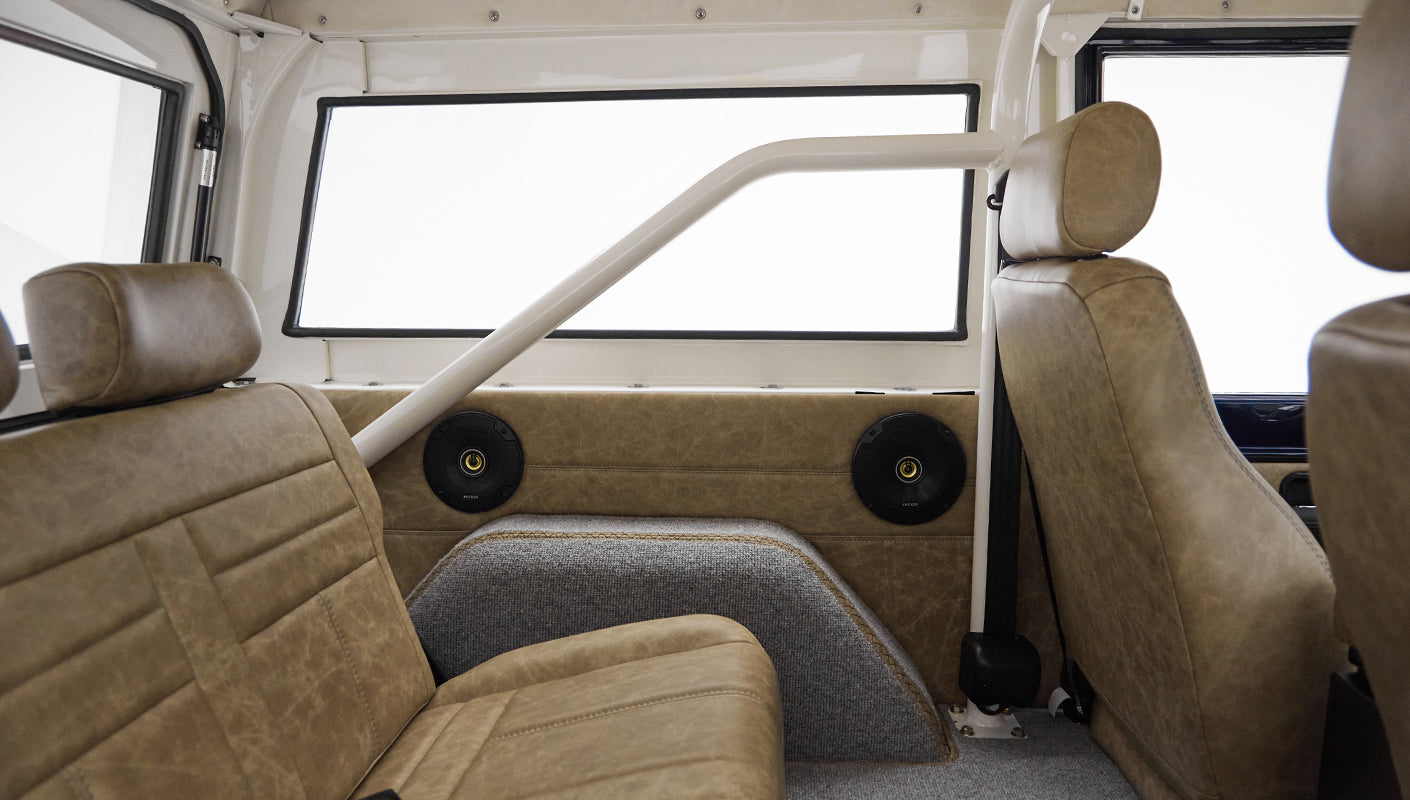 Rear passenger side view inside Classic Ford Bronco showing brown leather seats and speaker panels
