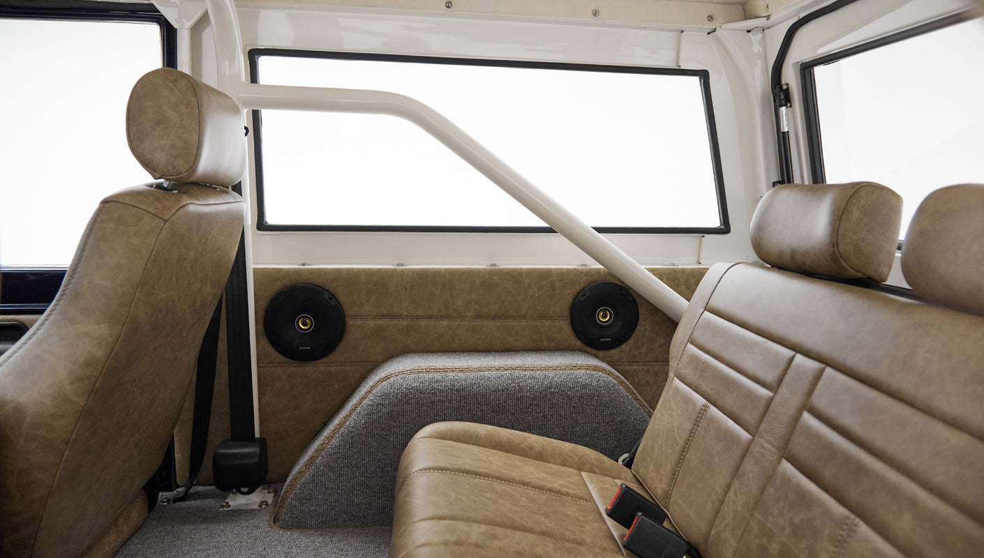Rear passenger area of Classic Ford Bronco with brown leather seats and speakers in side panels