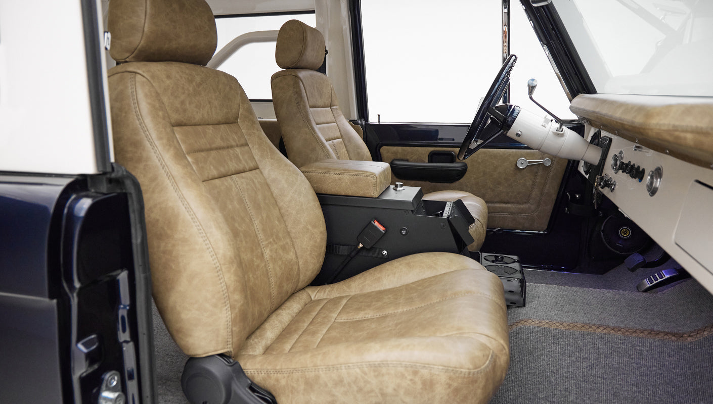 Interior front seats of Classic Ford Bronco with tan leather upholstery and black center console