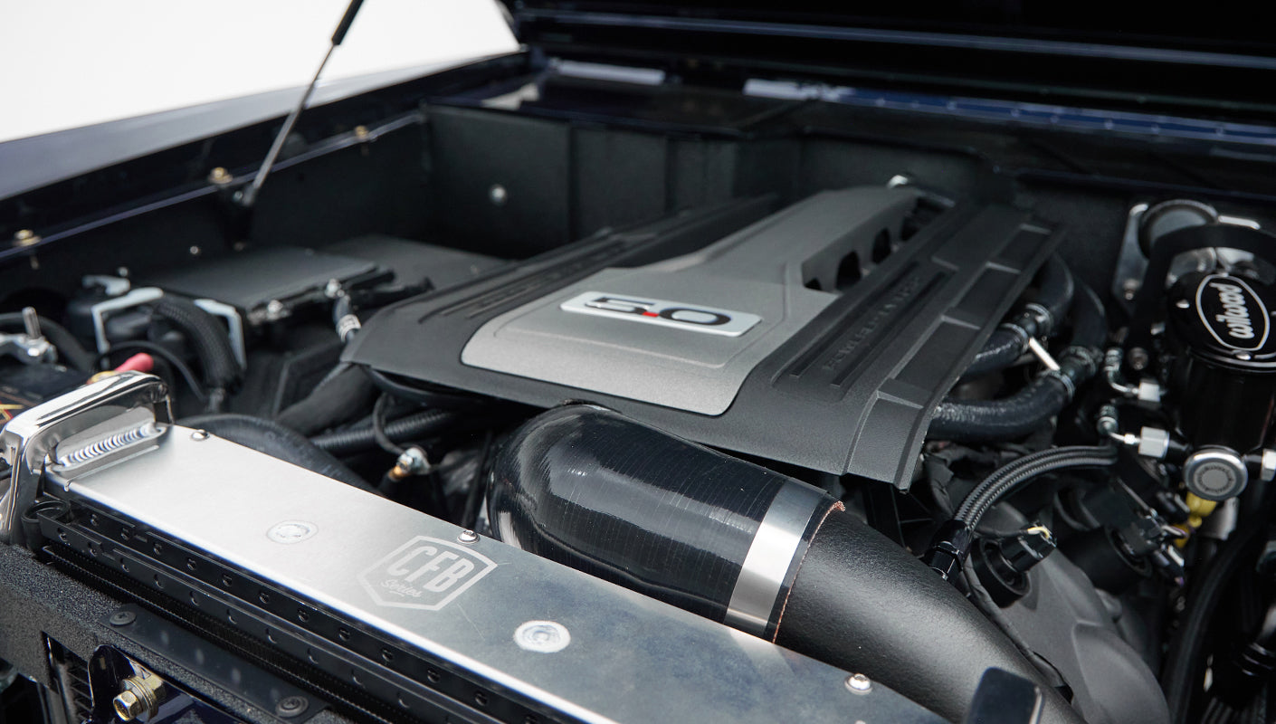 Classic Ford Bronco engine close-up with 5.0 emblem and air intake pipe