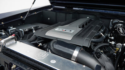 Classic Ford Bronco engine close-up with 5.0 emblem and air intake pipe