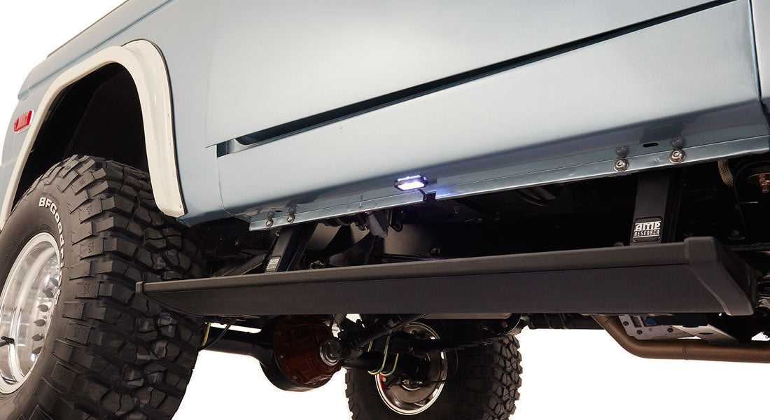 Underside side view of light blue Classic Ford Bronco showing suspension and large off-road tire