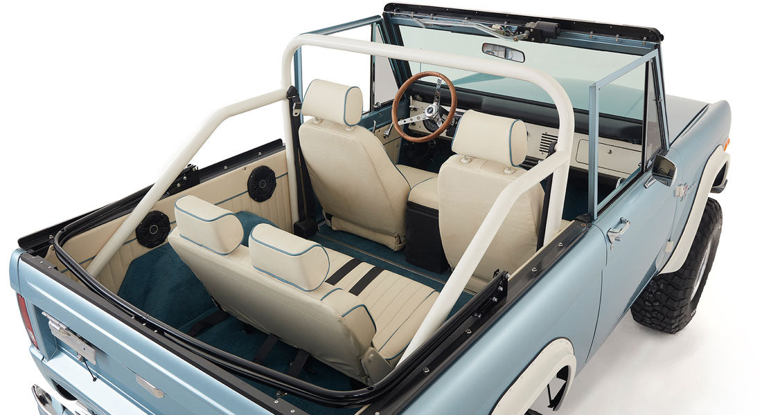 Top rear angle interior view of light blue Classic Ford Bronco with white roll cage and seats