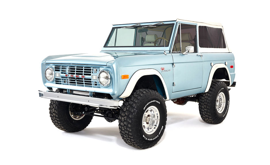 Light blue Classic Ford Bronco left side view with doors, wheel, and soft top on white background