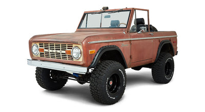 Rust-colored Classic Ford Bronco front three-quarter view with chrome bumper and off-road tires.