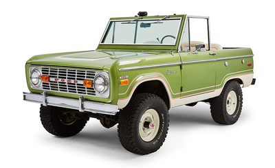 Green Classic Ford Bronco with chrome detailing and white wheels angled front driver side