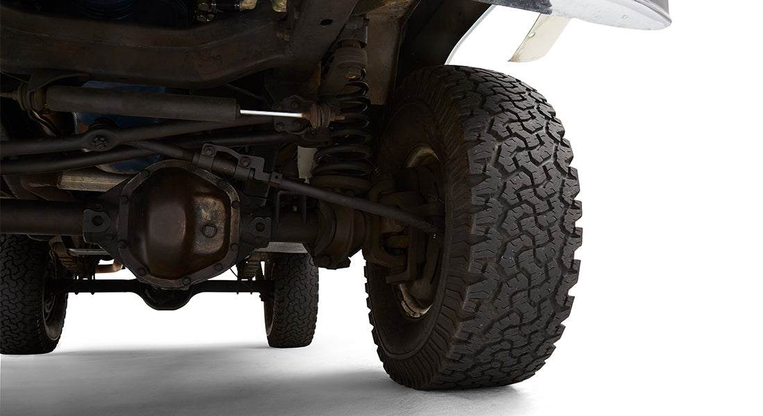 Close-up of front driver suspension and tire on a green Classic Ford Bronco