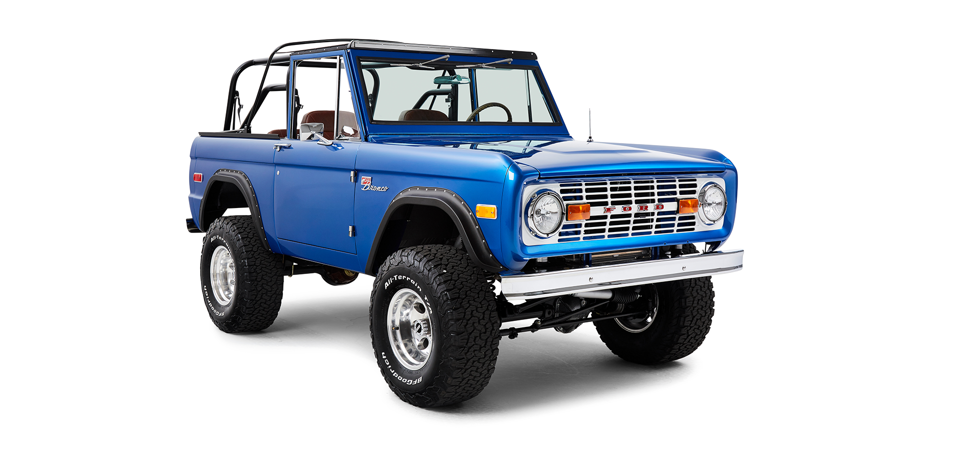 Front passenger angle view of blue Classic Ford Bronco with off-road tires and open roll cage