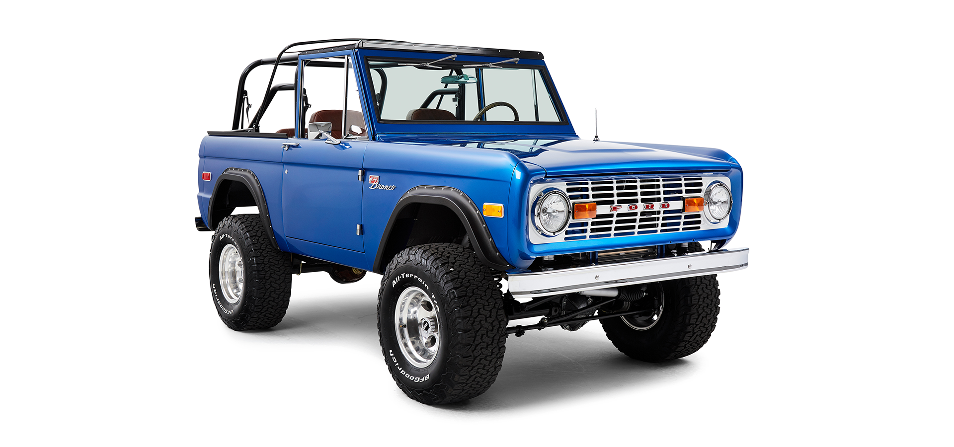 Blue Classic Ford Bronco front passenger angled view showing grille, round headlights, and off-road tires