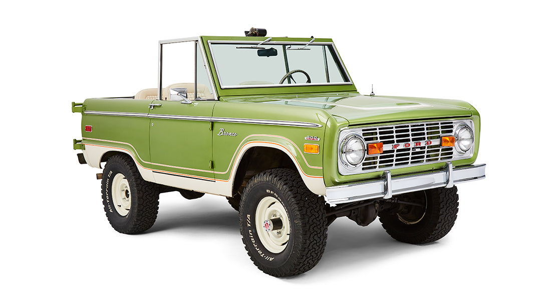 Front passenger angle view of a green Classic Ford Bronco with white wheels and lifted body