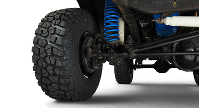 Close-up of front passenger side suspension with large off-road tire and blue coil spring