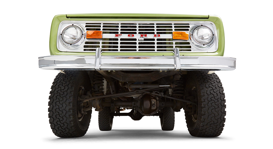 Undercarriage view of green Classic Ford Bronco front suspension and tires