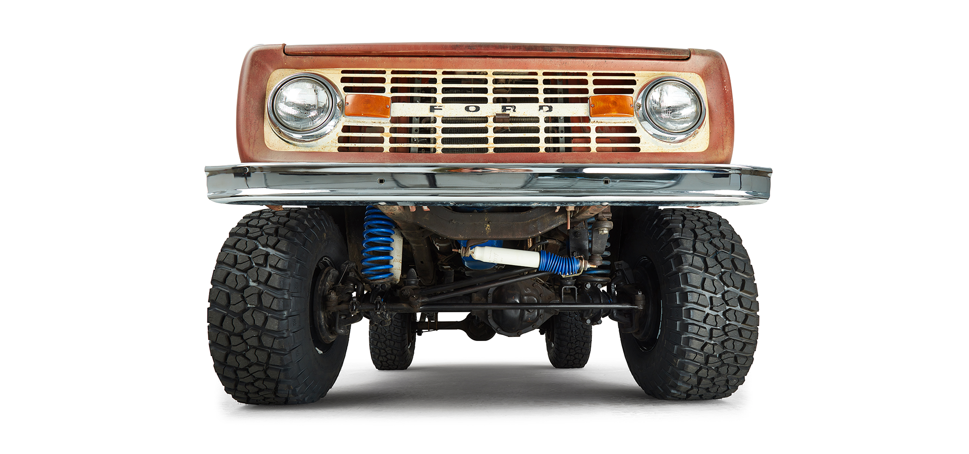 Undercarriage and front suspension of a red Classic Ford Bronco shown from low front