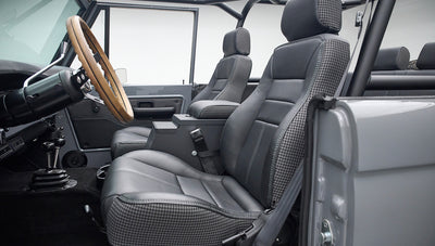 Front seats and dashboard inside Classic Ford Bronco with wood steering wheel and houndstooth seating